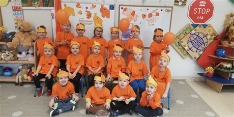 Powiększ grafikę: Zdjęcia przedtawia dzieci w sali przedszkolnej ubrane w pomarańczowe koszulki ,na głowach dzieci mają pomarańczowe opaski ze słoniem pomarańczowym 