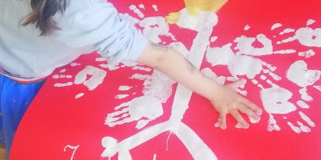Powiększ grafikę: Na zdjęciu dziecko odciskające dłoń na palkacie z orłem białym