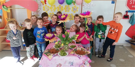 Powiększ grafikę: Na zdjęciu uśmiechnięte dzieci w ieku przedszkolnym z kwiatkami w dłoniach obchodzących dzień kobie