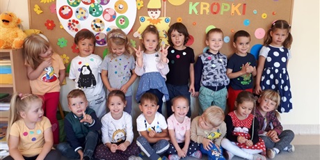 Powiększ grafikę: Na zdjęciu grupa dzieci w wieku przedszkolnymnW tle kolorowe kropki.