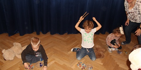 Powiększ grafikę: Na zdjęciu dzieci w wieku przedszkolnym układające szklane kolorowe kulki drewnianymi szczypcami.