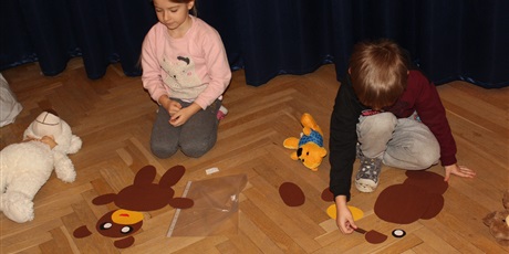 Powiększ grafikę: Na zdjęciu dziecko w wieku przedszkolnym układające puzle  postaci papierowych misi 