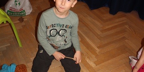 Powiększ grafikę: Na zdjęciu dziecko w wieku przedszkolnym układające szklane kulki drewnianą łyżeczką