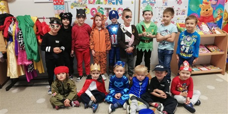 Powiększ grafikę: Zdjęcie przedstawia chłopców w wieku  przedszkolnym przebranych w kolorowe stroje postaci z bajek stojące w rzędzie w sali przedszkolnej.