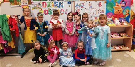Powiększ grafikę: Zdjęcie przedstawia dziewczynki w wieku  przedszkolnym przebrane w kolorowe stroje postaci z bajek stojące w rzędzie w sali przedszkolnej.