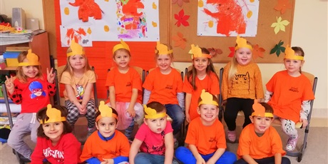 Powiększ grafikę: Na zdjęciu grupa dzieci w wieku przedszkolnym z opaskami ze słoniami w kolorze pomarańczowym.
