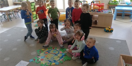 Powiększ grafikę: Grupa dzieci w wieku przedszkolnym podczas zaęć na dywanie z kolorowym plakacie kuli ziemskiej.