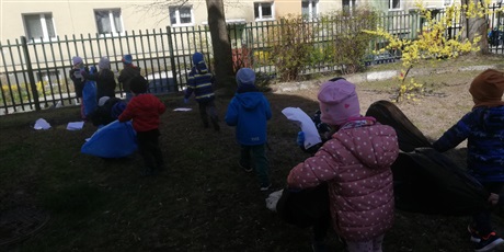 Powiększ grafikę: Na zdjęciu grupa dzieci w wieku przedszkolnym sprzątająca teren przedszkola.