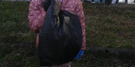 Powiększ grafikę: Na zdjęciu dziewczynka z workeim na śmieci.