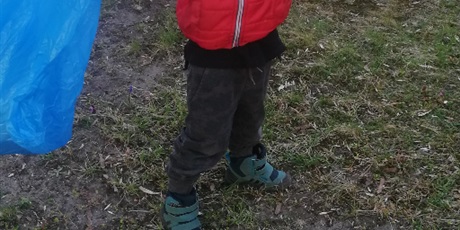 Powiększ grafikę: Na zdjęciu chłopiec w czerwonej kurtce z workiem na śmieci 