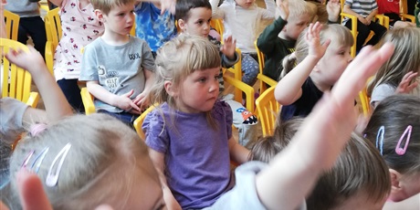 Powiększ grafikę: Na zdjęciu grupa dzieci w wieku przedszkolnym na sali gimnastycznej pdczas  oglądania muzycznego.