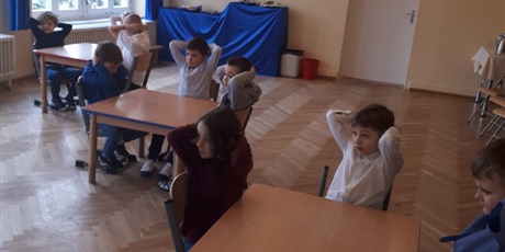 Powiększ grafikę: Na zdjęciu grupa dzieci siedząca na sali gmnastycznej podczas konkursu matematycznego.