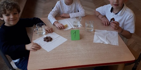 Powiększ grafikę: Na zdjęciu grupa dzieci siedząca na sali gmnastycznej podczas konkursu matematycznego