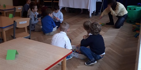 Powiększ grafikę: Na zdjęciu grupa dzieci siedząca na sali gmnastycznej podczas konkursu matematycznego