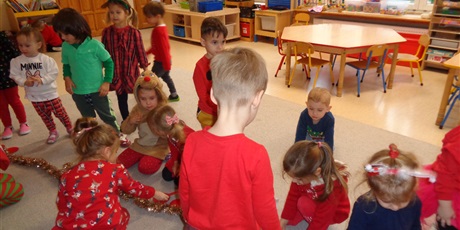 Powiększ grafikę: Na zdjęciu grupa dzieci w wieku przedszkolnym bawiących się na dywanie podczas zabaw mikołjkowych