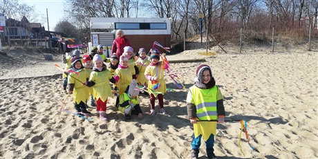 Powiększ grafikę: Na zdjęciu dzieci w żółtych strojach na plaży witający wiosnę.