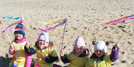 Powiększ grafikę: Na zdjęciu dzieci w żółtych strojach na plaży nad morzem witający wiosnę.