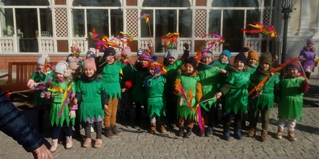 Powiększ grafikę: Na zdjęciu dzieci maszerujący ulicą w kolorowych strojach, śpiewające piosenki o wiośnie i witające wiosnę.