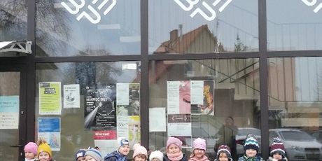 Powiększ grafikę: Na zdjęciu grupa dzieci w wieku przedszkolnym na tle biblioteki osiedlowej