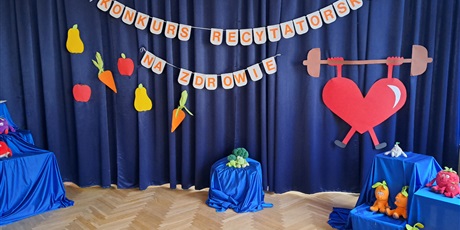 Powiększ grafikę: Na zdjęciu dekoracja na sali gimnastycznej na granatowym materiale i pluszowe owoce