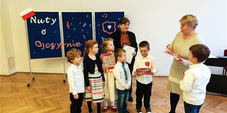 Powiększ grafikę: Na zdjęciu grupa dzieci z ksiązkami w dłoniach i dwie kobiety.
