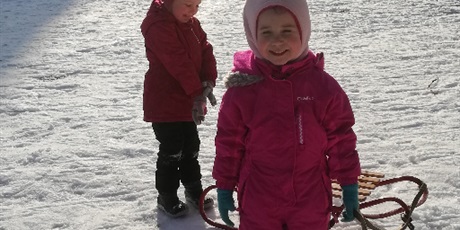 Powiększ grafikę: Na zdjęciu dzieci ubrane w kombinezony podczas zabaw na śniegu.