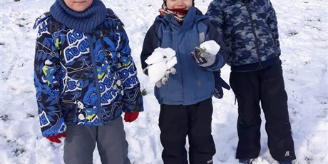 Powiększ grafikę: Na zdjęciu dzieci ubrane w kombinezony podczas zabaw na śniegu.