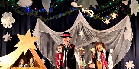 Powiększ grafikę: Na zdjęciu aktor z pacynkami  i aktorka z pacynkami w tle szopka bożonarodzeniowa.