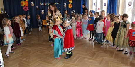 Powiększ grafikę: Na zdjęciu grupa dzieci w strojach karnawałowych podczas zabaw z okazji tłustego czwartku oraz król i królowa pączków