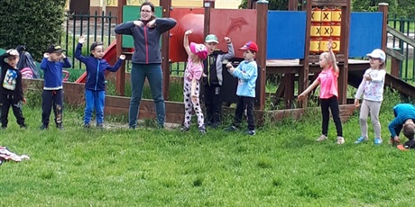 Powiększ grafikę: Na zdjęciu grupa dzieci stojących na przedszkolnym placu zabaw podczas zabaw sportowych.