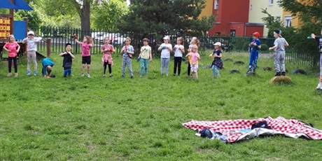 Powiększ grafikę: Na zdjęciu grupa dzieci stojących na przedszkolnym placu zabaw podczas zabaw sportowych