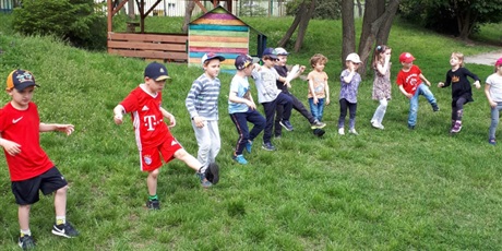 Powiększ grafikę: Na zdjęciu grupa dzieci w wieku przedszkolnym stojąca na trawie zielonej podczs zabaw sportowych.