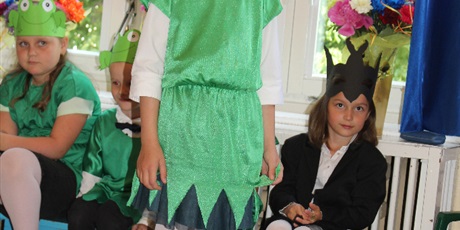 Powiększ grafikę:  Na zdjęciu dzieci w wieku przedszkolnym w kolorowych strojach żabki i jaskółki  podczas przedstawienia z okazji zakończenia roku przedszkolnego