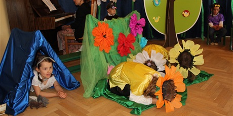 Powiększ grafikę: Na zdjęciu dzieci w wieku przedszkolnym w kolorowych strojach kwiatków,  myszki, podczas przedstawienia z okazji zakończenia roku przedszkolnego