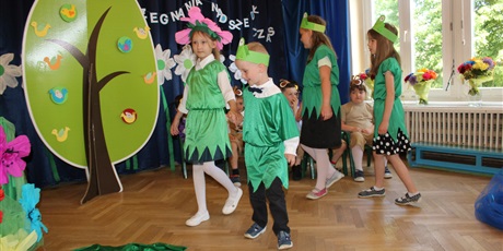 Powiększ grafikę: Na zdjęciu dzieci w wieku przedszkolnym w kolorowych strojach podczas przedstawienia z okazji zakończenia roku przedszkolnego