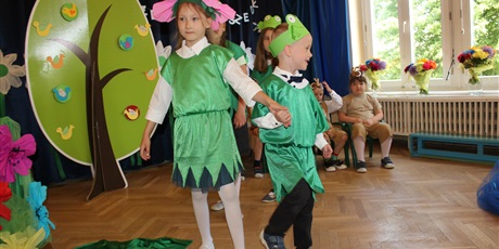 Powiększ grafikę: Na zdjęciu dzieci w wieku przedszkolnym w kolorowych strojach podczas przedstawienia z okazji zakończenia roku przedszkolnego.