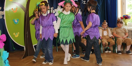 Powiększ grafikę: Na zdjęciu dzieci w wieku przedszkolnym w kolorowych strojach podczas przedstawienia z okazji zakończenia roku przedszkolnego.