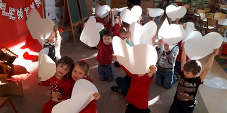 Powiększ grafikę: Na zdjęciu dzieci podczas zabaw walentynkowych z białymi sercami papierowymi w dłoniach.