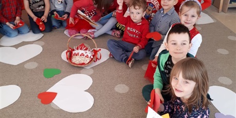 Powiększ grafikę: Na zdjęciu dzieci w wieku przedszkolnym   .Na dywanie leżą białe papierowe  serca.