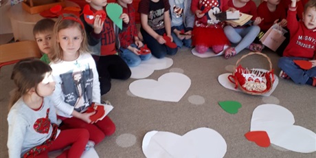 Powiększ grafikę: Na zdjęciu dzieci w wieku przedszkolnym   .Na dywanie leżą białe papierowe  serca.