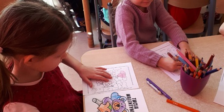 Powiększ grafikę: Na zdjęciu dzieci w wieku przedszkolnym podczas zabaw walentynkowych kolorujące obrazek misia z serduszkiem.