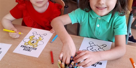Powiększ grafikę: Na zdjęciu dzieci w wieku przedszkolnym podczas zabaw walentynkowych kolorujące obrazek misia z serduszkiem