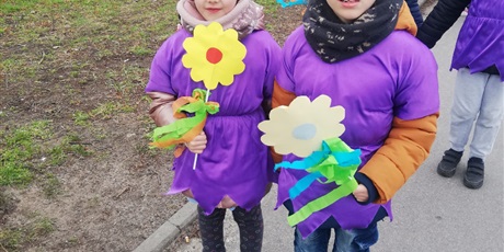 Powiększ grafikę: Na zdjęciu grupa dzieci w wieku przedszkolnym w strojach fioletowych z kwiatkami  witająca wiosnę