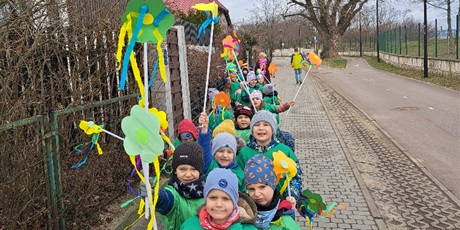 Powiększ grafikę: Na zdjęciu grupa dzieci w wieku przedszkolnym w strojach zielonych z kwiatkami  witająca wiosnę