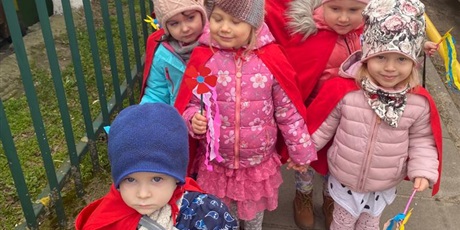 Powiększ grafikę: Na zdjęciu grupa dzieci w wieku przedszkolnym w strojach czerwonych z kwiatkami  witająca wiosnę.