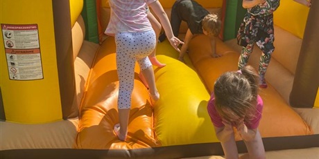 Powiększ grafikę: Na zdjęciu dmuchana żółta zabawaka i skaczące w nim dzieci w wieku przedszkolnym.