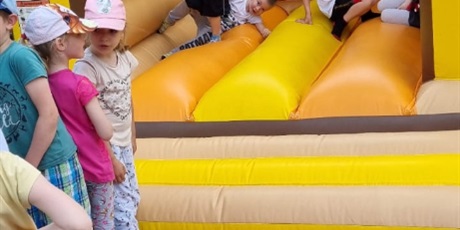 Powiększ grafikę: Na zdjęciu dmuchana żółta zabawaka i skaczące w nim dzieci w wieku przedszkolnym.