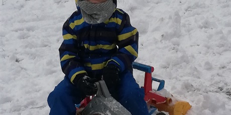 Powiększ grafikę: Chłopiec bawiący się śniegiem i siedzący na koparce 
