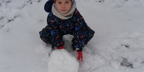 Powiększ grafikę: Chłopiec toczący kulę śnieżną