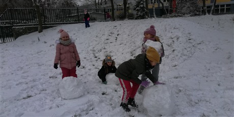 Powiększ grafikę: Dzieci podczas zabaw na śniegu toczący duże kule śnieżną